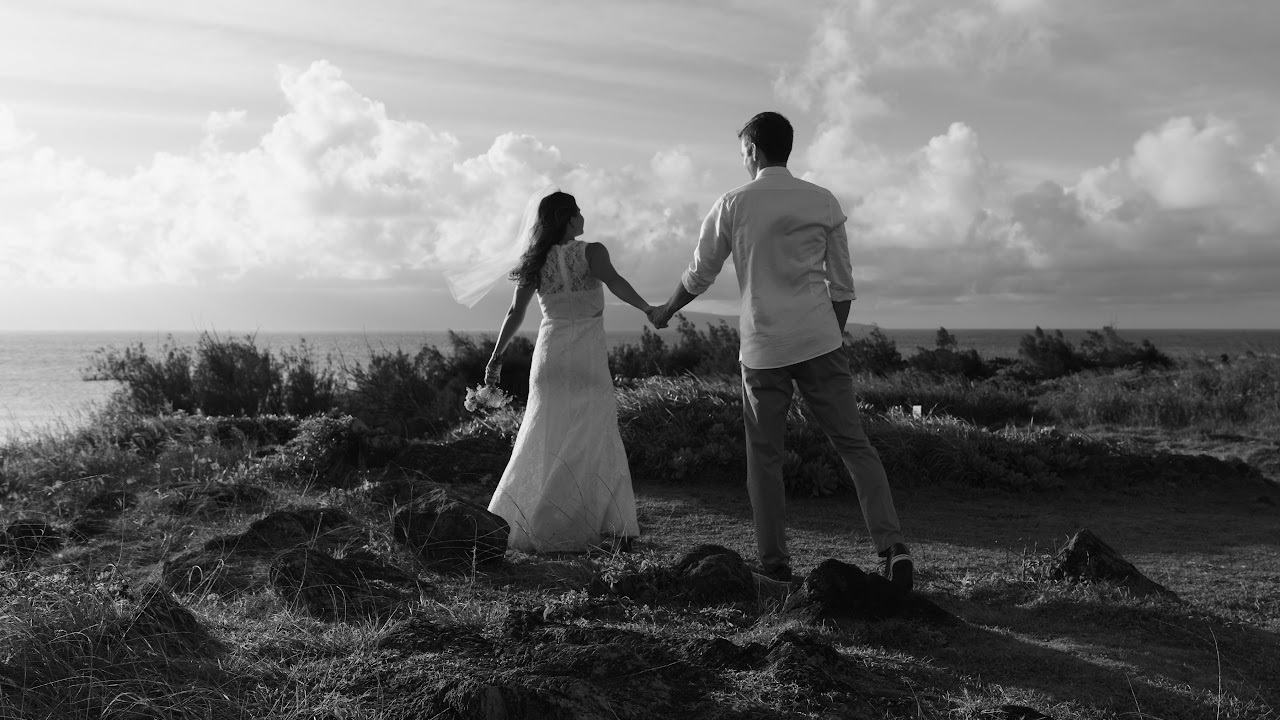 A couple holding hands, walking toward the coast at dusk